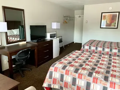 a hotel room with a bed and a desk and a mirror at Milestone Motel in Collingwood