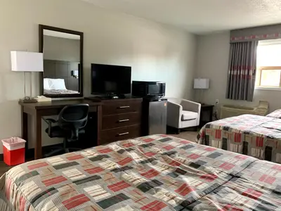 a hotel room with a bed and a desk and a mirror at Milestone Motel in Collingwood