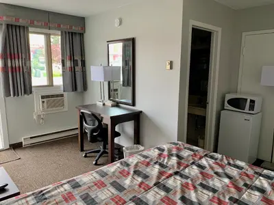 a hotel room with a bed and a desk in a room at Milestone Motel in Collingwood