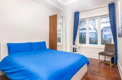 a bedroom with a blue bed and a chair at Hillcrest Modern House in Toronto