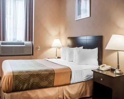 a hotel room with a bed and a phone at Woodstock Inn and Suites in Woodstock