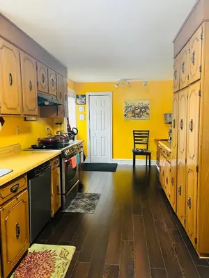 a kitchen with yellow walls and wooden cabinets at Cozy House B&B in Niagara Falls