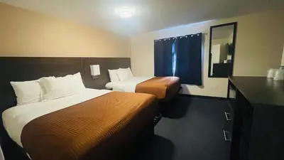 a hotel room with two beds and a mirror at Falls Lodge & Suites in Niagara Falls