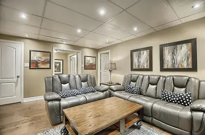 a living room with a leather couch and a table at 6 Bedroom Executive Cottage near Innisfil Beach Park in Innisfil