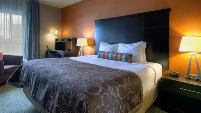 a hotel room with a large bed and a chair at Staybridge Suites Hamilton - Downtown by IHG in Hamilton