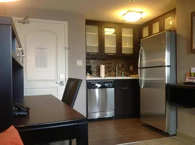 a kitchen with a stainless steel refrigerator and a table at Staybridge Suites Hamilton - Downtown by IHG in Hamilton