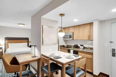 a room with a bed and a kitchen with a table at Homewood Suites by Hilton Toronto-Markham in Markham