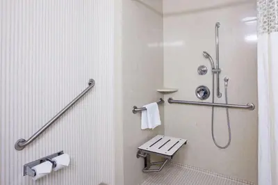 a bathroom with a shower and a bench in it at Hampton Inn & Suites by Hilton Toronto Airport in Mississauga