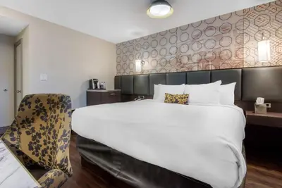 a hotel room with a large bed and a chair at The Champlain Waterfront Hotel, an Ascend Collection Hotel in Orillia