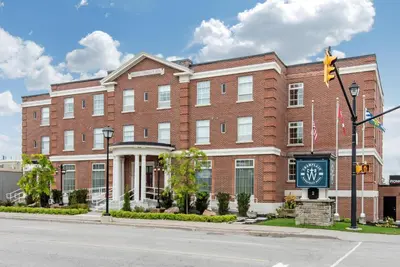 a large brick building with a clock in front of it at The Champlain Waterfront Hotel, an Ascend Collection Hotel in Orillia