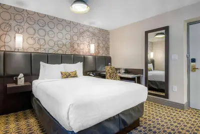 a hotel room with a large bed and a mirror at The Champlain Waterfront Hotel, an Ascend Collection Hotel in Orillia
