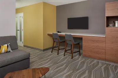 a living room with a couch and a bar with a tv at Hilton Toronto Airport Hotel & Suites in Mississauga