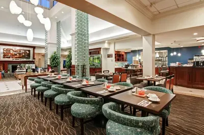 a restaurant with wooden tables and green chairs at Hilton Garden Inn Toronto/Burlington in Burlington