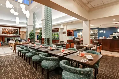 a restaurant with wooden tables and green chairs at Hilton Garden Inn Toronto/Burlington in Burlington