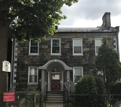 an old brick house with a red door at Pring Guesthouse in Hamilton