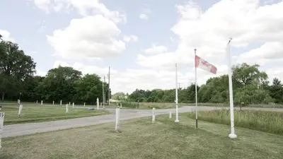 a row of white poles with a flag on a road at Pleasant Stay Motel in Ancaster