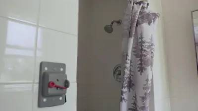 a shower curtain in a bathroom with a red button at Pleasant Stay Motel in Ancaster