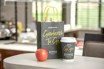 a bag and a cup of coffee and an apple on a table at Staybridge Suites Toronto - Vaughan South by IHG in Vaughan