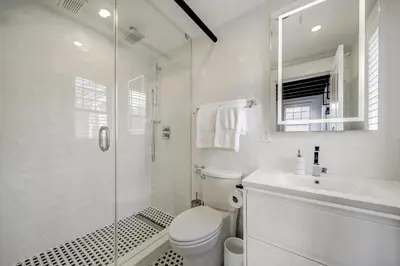 a white bathroom with a shower and a toilet and a sink at The Westlake in Toronto
