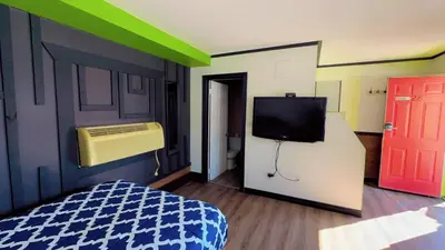 a bedroom with a bed and a tv and a door at Crestwood Motel in Burlington