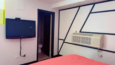 a bedroom with a bed and a tv and a fan at Crestwood Motel in Burlington