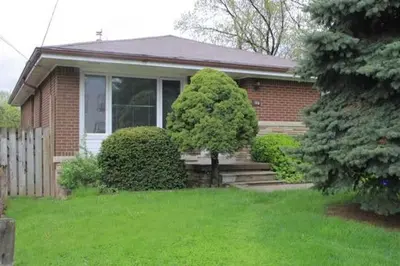 a small brick house with a tree in the front yard at McMaster Accommodations in Hamilton