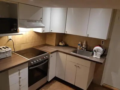 a small kitchen with white cabinets and a sink at McMaster Accommodations in Hamilton