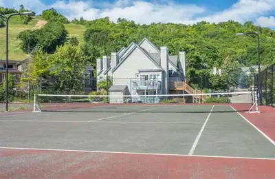 a tennis court with a house in the background at Blue Mountain Getaway at North Creek Resort King Bed in Blue Mountains