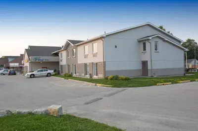 a building with a car parked in a parking lot at The Village Inn in Elora