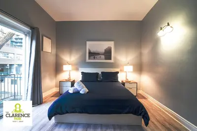a bedroom with a large bed and two lamps at The Clarence Park in Toronto