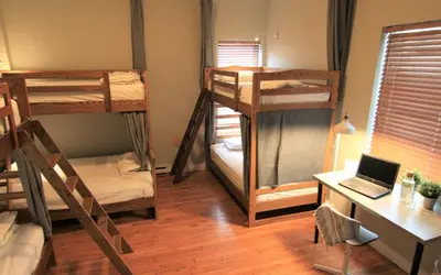 a room with three bunk beds and a desk with a laptop at The Clarence Park in Toronto