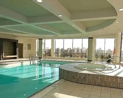a large swimming pool with blue water in a building at Mississauga Furnished Apartments in Mississauga