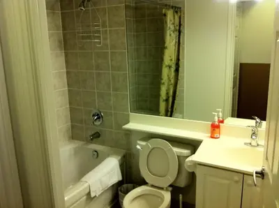 a bathroom with a toilet and a tub and a sink at Mississauga Furnished Apartments in Mississauga