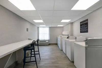 a laundry room with machines and a bar with a chair at Homewood Suites by Hilton London Ontario in London
