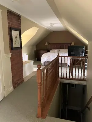 a attic bedroom with a bed and a staircase at The Red Coat in Niagara on the Lake