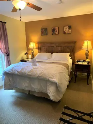 a bedroom with a large bed with two tables and two lamps at The Red Coat in Niagara on the Lake