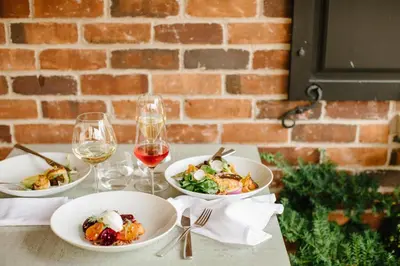 a table with three plates of food and wine glasses at 124 on Queen Hotel & Spa in Niagara on the Lake