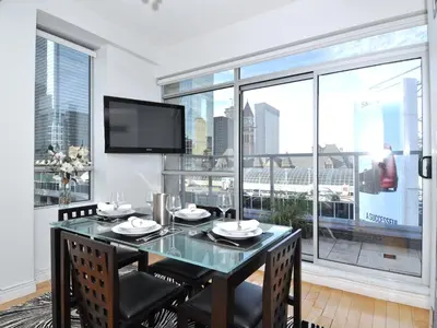 a dining room with a table and a large window at Yonge Suites Apart Hotel in Toronto