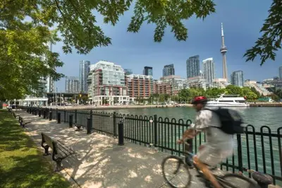 a man riding a bike next to a body of water at Yonge Suites Apart Hotel in Toronto