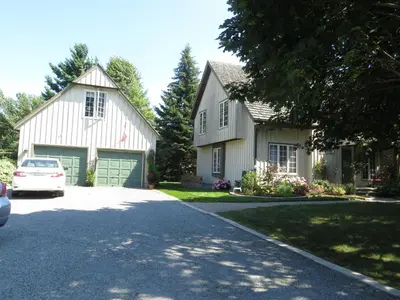 a white house with a car parked in a driveway at Cedar Gables Bed & Breakfast in Niagara on the Lake