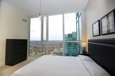 a bedroom with a large white bed and a large window at Pathway Suites in Mississauga