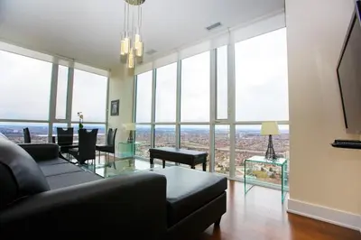a living room with a couch and tables and windows at Pathway Suites in Mississauga