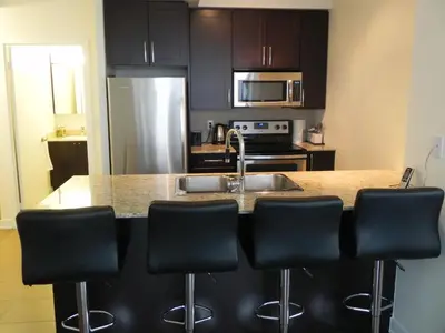 a kitchen with black cabinets and a kitchen island with bar stools at Pathway Suites in Mississauga