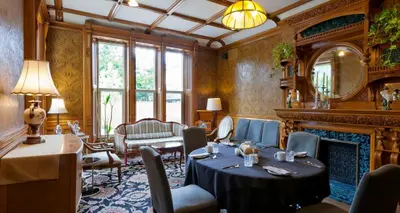 a dining room with a table and a fireplace at Idlewyld Inn & Spa in London