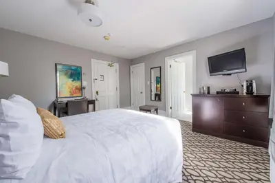 a bedroom with a white bed and a flat screen tv at Idlewyld Inn & Spa in London