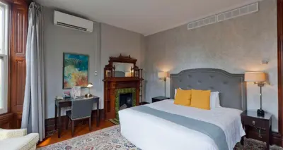 a bedroom with a bed with yellow pillows and a fireplace at Idlewyld Inn & Spa in London