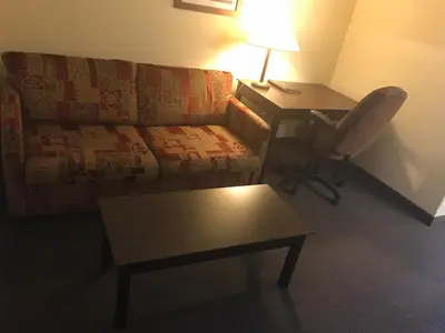 a living room with a couch and a desk with a lamp at Super 8 by Wyndham Barrie South in Barrie