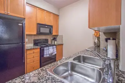 a kitchen with a stainless steel sink and a refrigerator at Platinum Suites Furnished Executive Suites in Mississauga