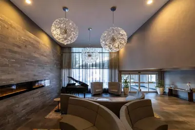 a living room with two chandeliers and a piano at Georgian Bay Hotel Trademark Collection by Wyndham in Collingwood