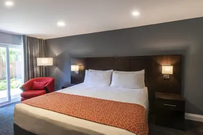 a hotel room with a bed and a red chair at Georgian Bay Hotel Trademark Collection by Wyndham in Collingwood